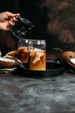 Şeffaf bardakta buzlu kahve ve hindistan cevizi sütü.