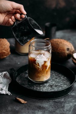 Şeffaf bardakta buzlu kahve ve hindistan cevizi sütü.