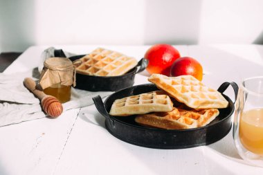 Beyaz tabakta ballı Belçika waffle 'ları ve portakal suyu. Kahvaltı