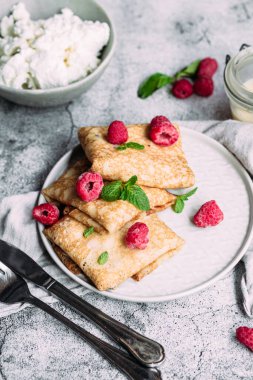 Ev yapımı süzme peynirli krep, ahududu, gri tabak.