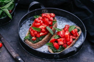  Pesto soslu sandviçler ve siyah arka planda domatesler.