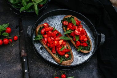  Pesto soslu sandviçler ve siyah arka planda domatesler.