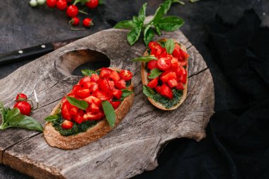  Pesto soslu sandviçler ve siyah arka planda domatesler.