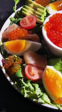 Beyaz tabakta alabalık, havyar, avokado, yumurta ve kırmızı havyar.