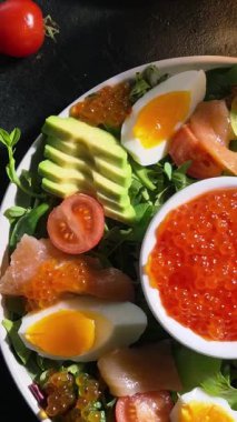 Salad with trout, caviar, avocado, eggs and red caviar in a white plate