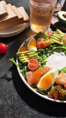 Salad with trout, caviar, avocado, eggs and red caviar in a white plate