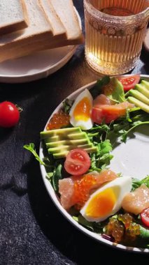 Salad with trout, caviar, avocado, eggs and red caviar in a white plate