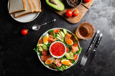 Gurme somon ve avokado salatası, koyu arkaplanda kırmızı havyar.