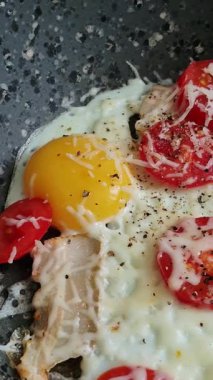 Çeri domatesli, pastırmalı ve tavada erimiş peynirli yumurta yakın plan..