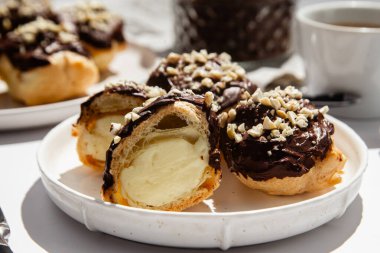 Masada beyaz bir tabakta kremalı profiterol. Kekler, kahve, tatlı..