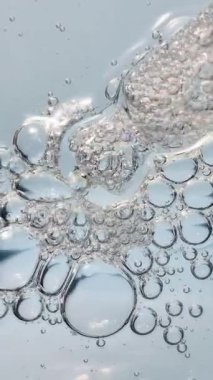 Makro şeffaf kozmetik jel, oksijen kabarcıkları ve cam damlaları. Cilt serumu ya da mavi arkaplanda hiyalüronik asit dokusu. 4k.