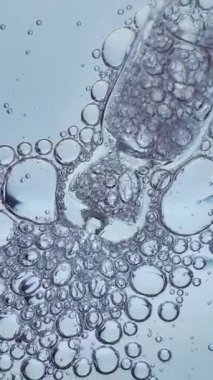 Makro şeffaf kozmetik jel, oksijen kabarcıkları ve cam damlaları. Cilt serumu ya da mavi arkaplanda hiyalüronik asit dokusu. 4k.