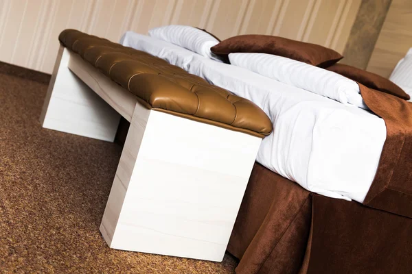 Gestoffeerde bruinleren voetbank op een bed — Stockfoto