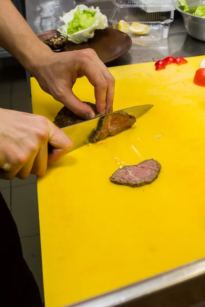 Bucătarul taie carnea din bucătărie — Fotografie, imagine de stoc