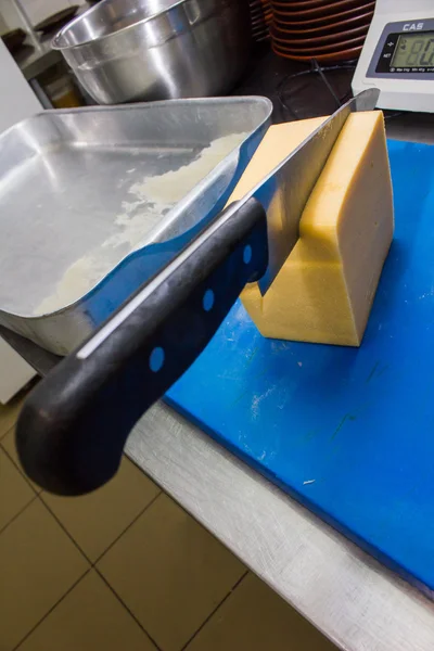 O chef corta o queijo na cozinha — Fotografia de Stock