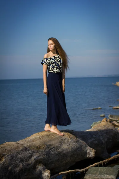 Fille sur la plage aux bûches — Photo