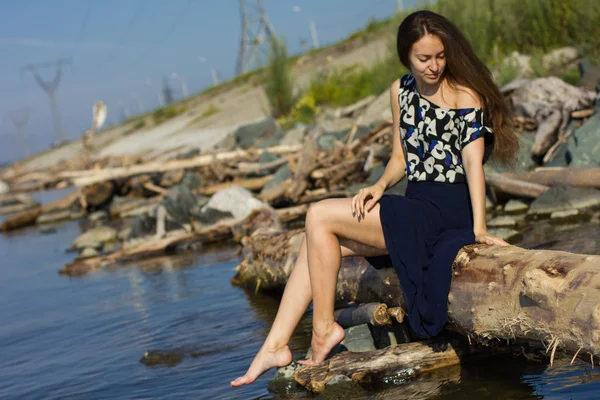 Flicka på stranden i loggarna — Stockfoto