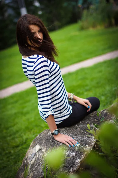 Menina em uma t-shirt está sentado em uma rocha — Fotografia de Stock
