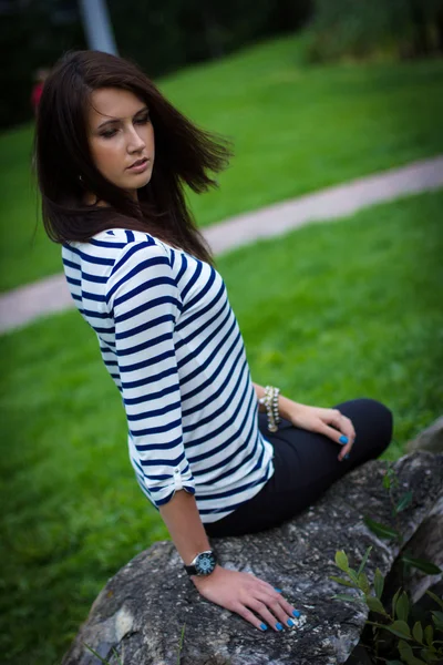 Girl in a t-shirt is sitting on a rock — Stock Photo, Image