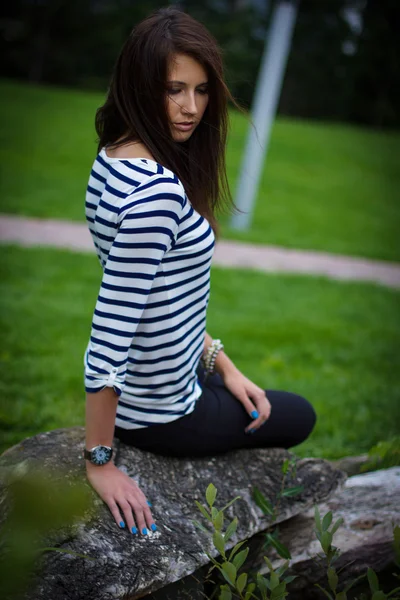 T-셔츠에서 여자 바위에 앉아 — 스톡 사진