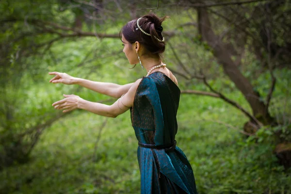 Girl in dress conjures in the forest — Stock Photo, Image