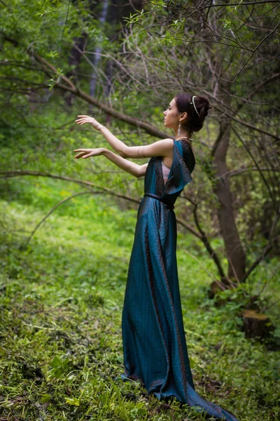 Girl in dress conjures in the forest — Stock Photo, Image