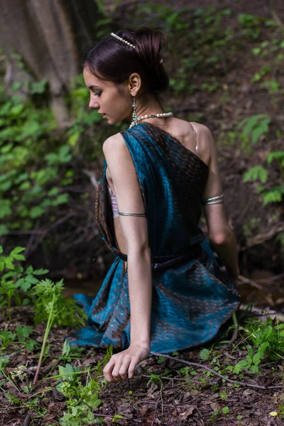 Tjej i klänning sitter i skogen — Stockfoto