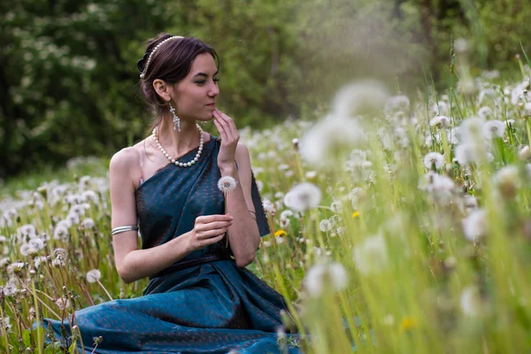 Fille en robe soufflant sur un pissenlit — Photo