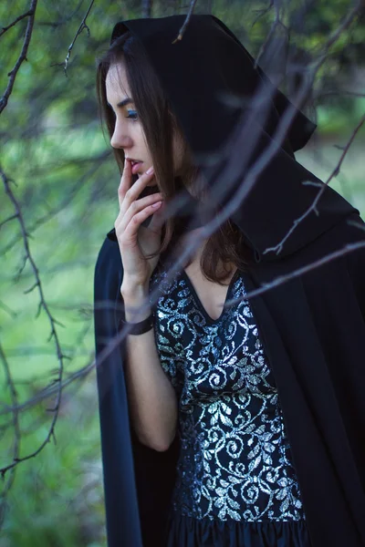 A menina com o manto preto na floresta — Fotografia de Stock