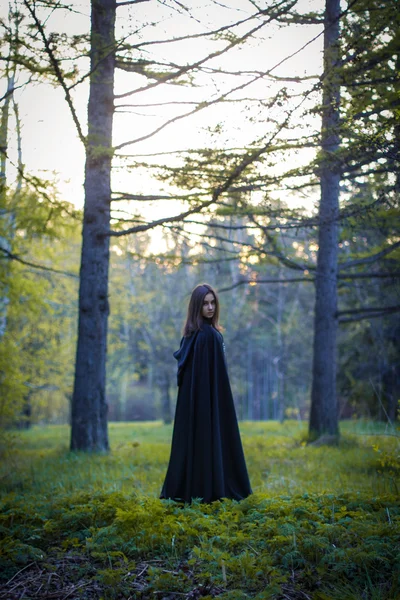 A menina com o manto preto na floresta — Fotografia de Stock