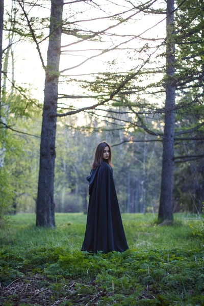 A menina com o manto preto na floresta — Fotografia de Stock