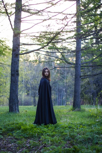 La chica con la capa negra en el bosque —  Fotos de Stock