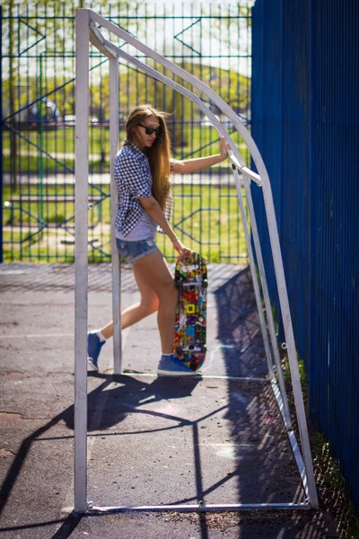 Söt tjej i shorts med en skateboard på lekplatsen — Stockfoto