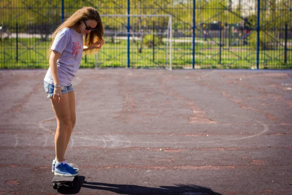 Söt tjej i shorts med en skateboard på lekplatsen — Stockfoto