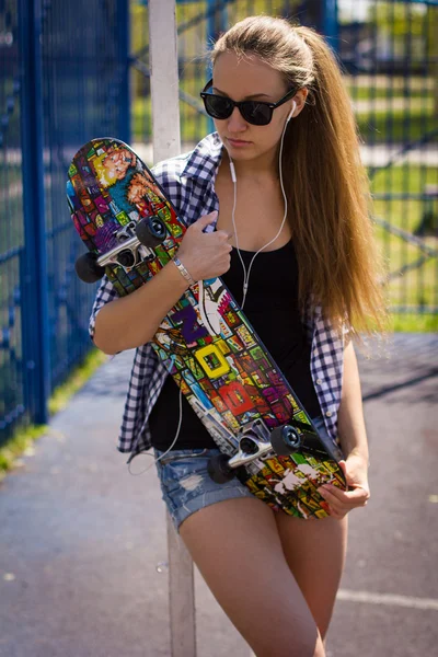 Милая девушка в шортах со скейтбордом на игровой площадке — стоковое фото