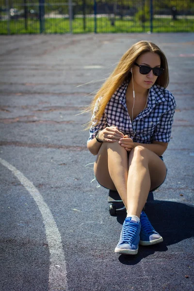 Menina bonito em shorts com um skate no parque infantil — Fotografia de Stock