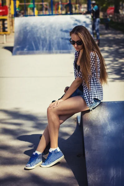 Linda chica en pantalones cortos con un monopatín en el patio de recreo — Foto de Stock