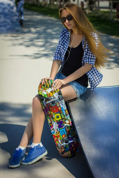 Linda chica en pantalones cortos con un monopatín en el patio de recreo — Foto de Stock