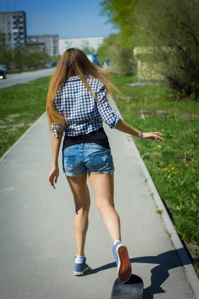 Chica en pantalones cortos montando un monopatín — Foto de Stock