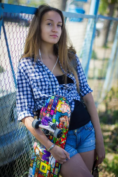 Ritratto di una ragazza in pantaloncini con skateboard — Foto Stock