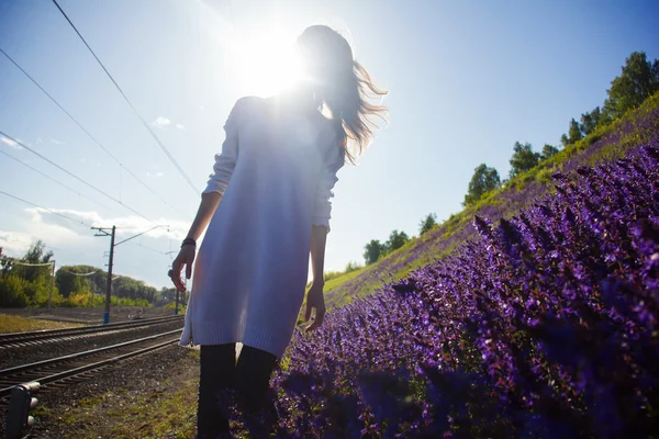 Dívka stojí poblíž louky s květinami — Stock fotografie