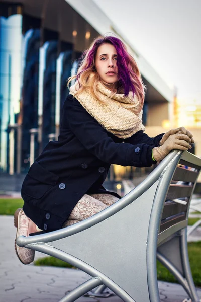 A menina no casaco sentado no banco — Fotografia de Stock