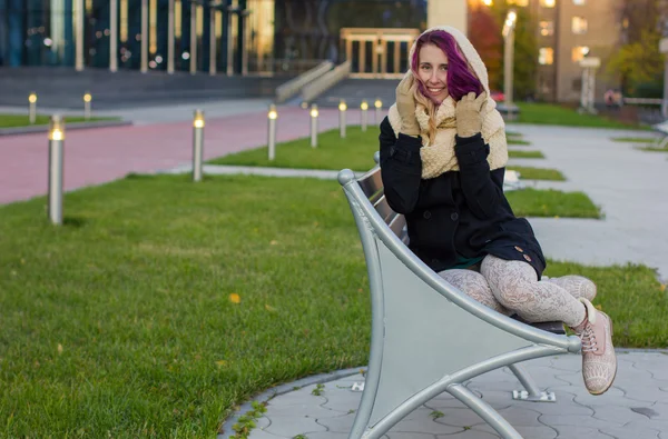 The girl in the coat sitting on the bench — Stock Photo, Image