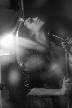 bir stüdyoda bir mikrofona şarkı söyleyen kız