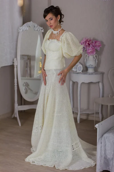 Невеста в белом платье возле стены — стоковое фото