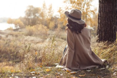 Kız ceket ve oturma ve mesafe içine seyir şapka