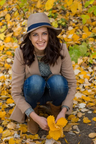 Mädchen im Mantel sammelt Blätter im Wald — Stockfoto