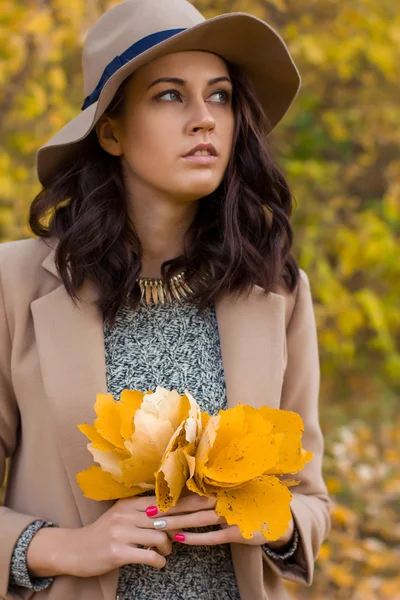 Fille dans le manteau recueille des feuilles dans la forêt — Photo