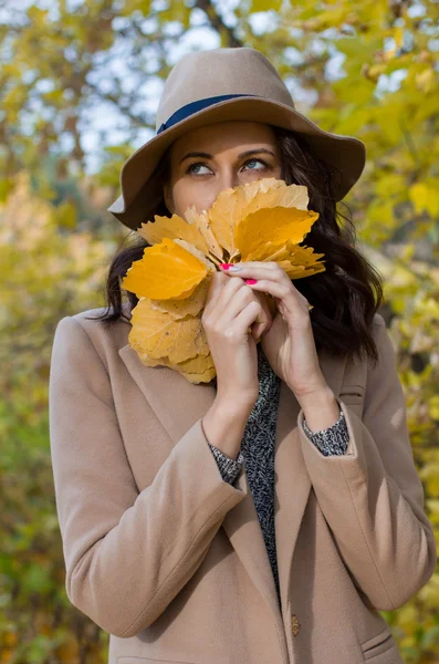 Fille dans le manteau recueille des feuilles dans la forêt — Photo