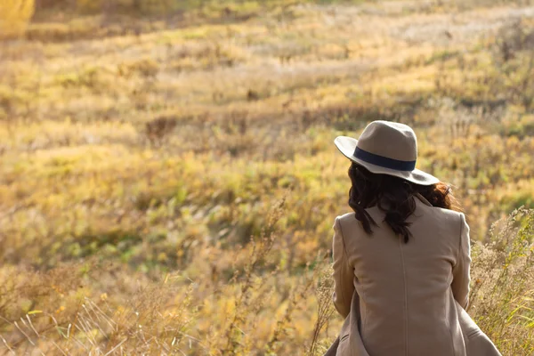 Chica con abrigo y sombrero sentado y mirando a la distancia —  Fotos de Stock